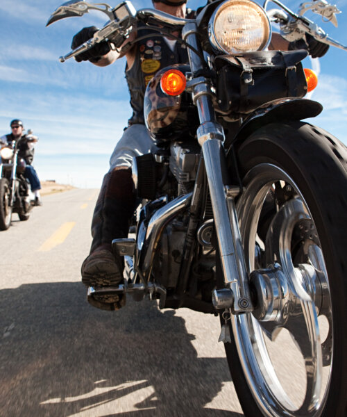 Two men riding motorcycles along road