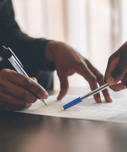 Cropped shot of an unrecognizable man filling a document with the help of a financial advisor at home