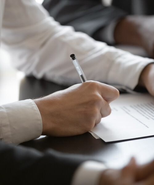 Close up young male employee manager customer hands signing paper contract after checking. Millennial investor client put signature at business agreement between partners. Editor making corrections.