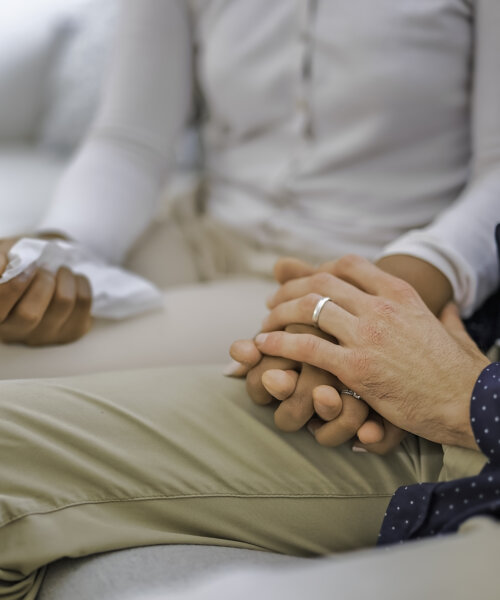 A hand holding tissue of a couple sit on sofa