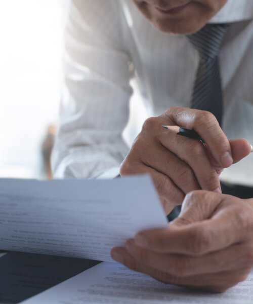 Businessman reading carefully terms, conditions of business contract, close-up. Business man proofing paper documents with laptop computer on table at office