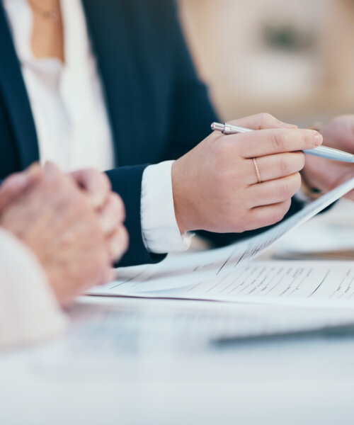 Hands working, reading and writing on business meeting notes in an office boardroom. Closeup view of corporate executive team doing work. Management group looking through finance data together