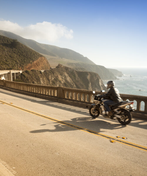 Motorcyclist on Bixby Bridge on highway 1 near the rocky Big Sur coastline of the Pacific Ocean California, USA