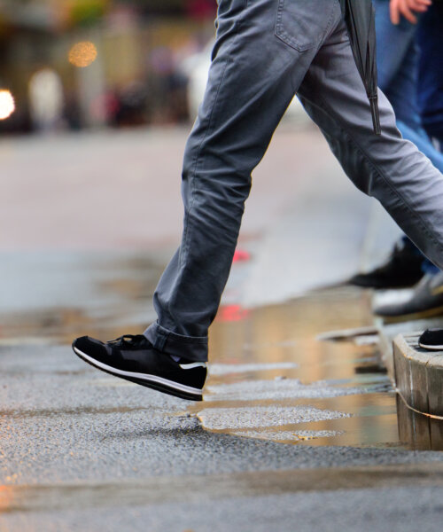 Man stepping over puddle in rain