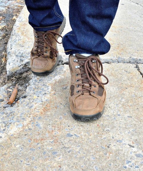 A low angle close up shot, showing a dangerous and neglected sidewalk, even showing a steel support rod protruding through the concrete.