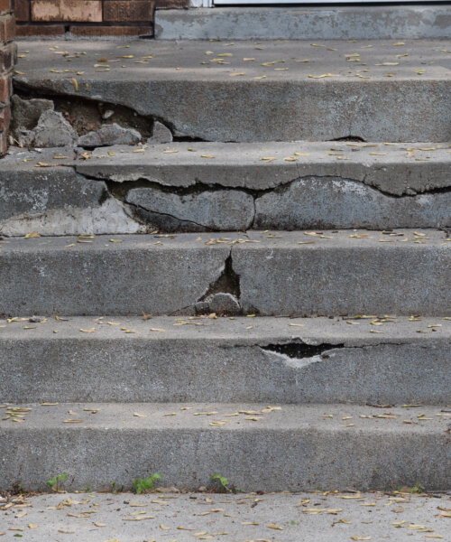 Short set of cement steps is cracked and broken and in need of repair