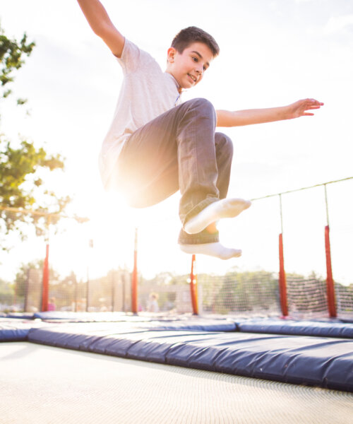 Photo of boy jumping open arms on the trampoline in the park