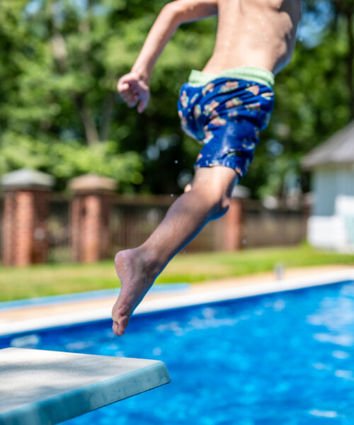 Selective focus on a swimming board as a young boy jumps into a pool. . High quality photo