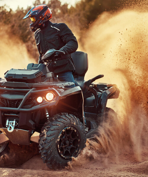 Teen riding ATV in sand dunes making a turn in the sand