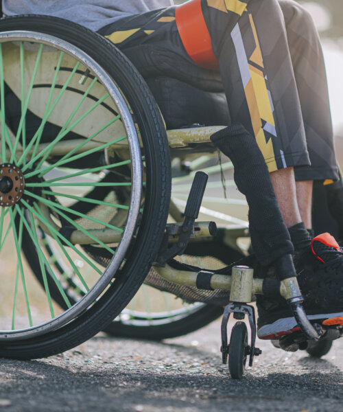 low section disabled Asian Indian man in wheelchair exercising in public park routine sport training in the morning