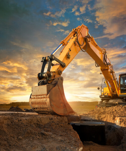 Excavator at a construction site against the setting sun.