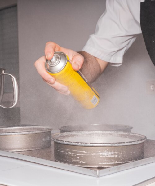 A man cooking a red velvet cake, spraying butter on the molds, work in the kitchen at home