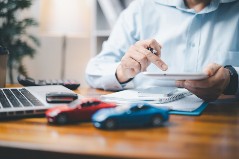 Red and blue toy cars in front of insurance adjuster using a calculator