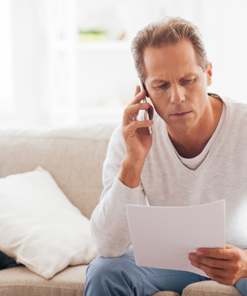 Serious mature man holding paper and talking on the mobile phone