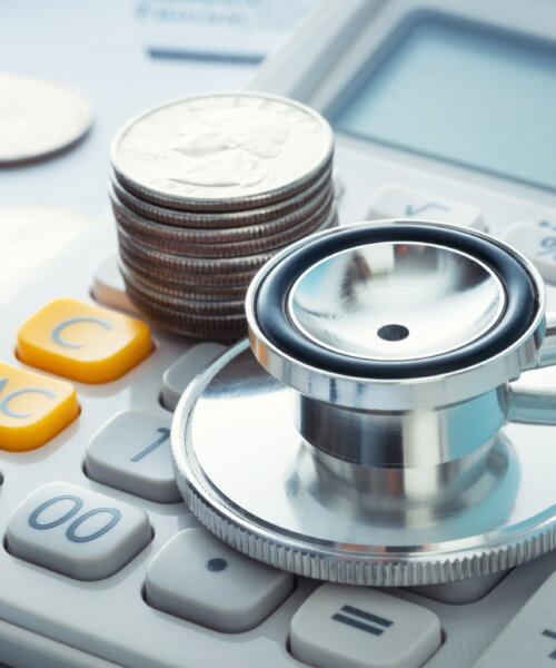 Stacked quarters and stethoscope on a calculator