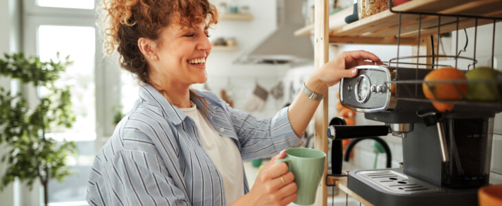 Young beautiful smiling woman making coffee in a domestic kitchen