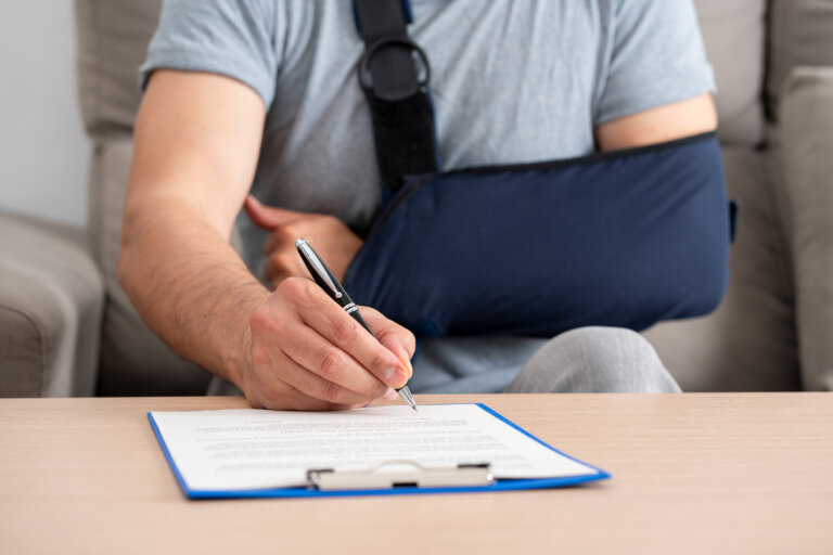 Front view of a handicapped man with sling signing contract at home