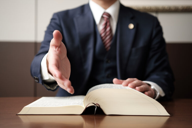 Lawyer reviewing a law book offering his hand for a handshake