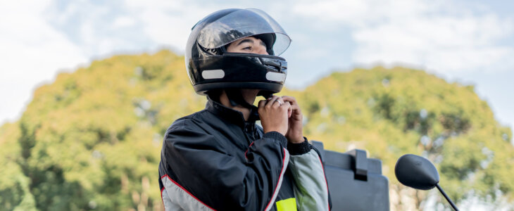 Delivery man removing motorcycle helmet, motoboy.