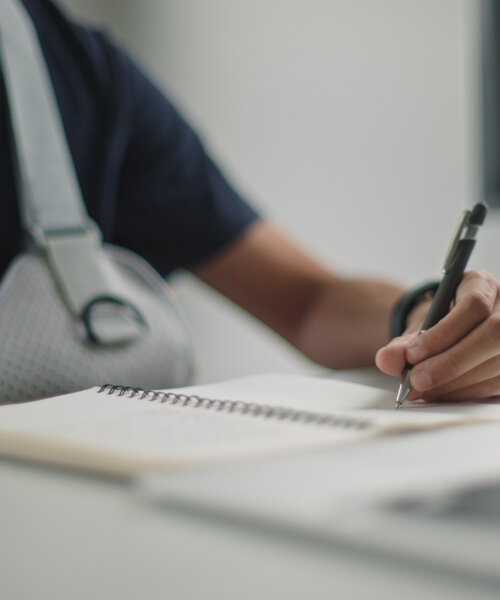 Asian young man learning online while wearing arm cast