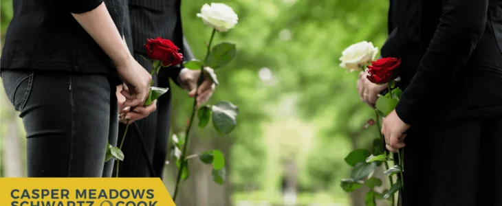 People dressed in black holding roses during a memorial service, with the Casper Meadows Schwartz & Cook law firm logo.