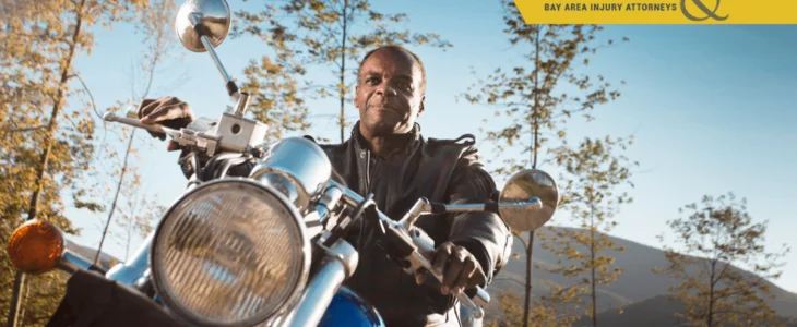 Confident man riding motorcycle through scenic mountain road in leather jacket