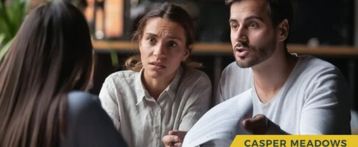Concerned couple discussing legal documents with a professional in an office setting.