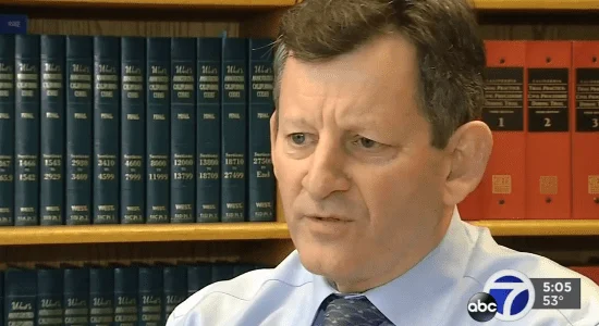 A man in a shirt and tie being interviewed in front of shelves of legal books, with an ABC7 news logo on screen.