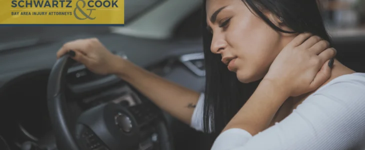 A woman sitting in a car grips the steering wheel with one hand and holds her neck in pain, branded with Casper Meadows Schwartz & Cook injury attorneys logo.
