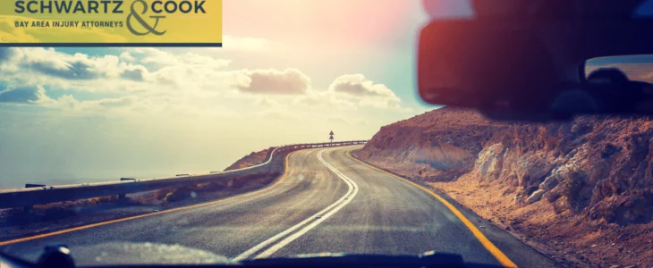 A scenic view of a winding road along rocky terrain seen from inside a car, branded with Casper Meadows Schwartz & Cook injury attorneys logo.