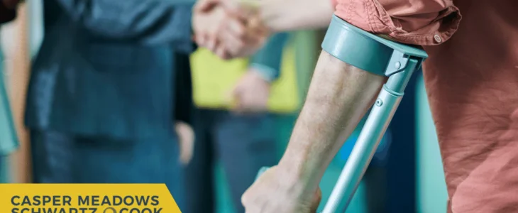 A person on crutches shaking hands with another individual, symbolizing legal or injury support, with the Casper Meadows Schwartz & Cook law firm logo.