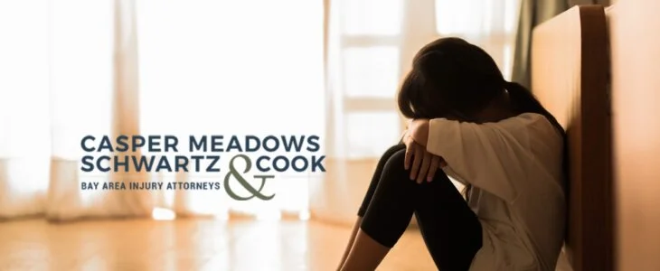 A young girl sitting on the floor with her head on her knees, appearing distressed, with the Casper Meadows Schwartz & Cook law firm logo.
