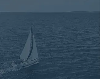 Sailboat gliding across open water with distant land on the horizon