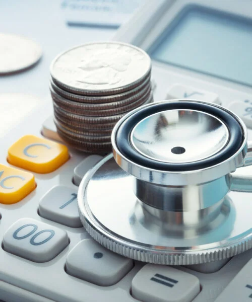 Stacked quarters and stethoscope on a calculator