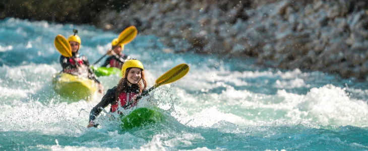 mid-adult thrill-seekers of mixed genders paddle fiercely through the white-capped rapids of a fast-flowing river.