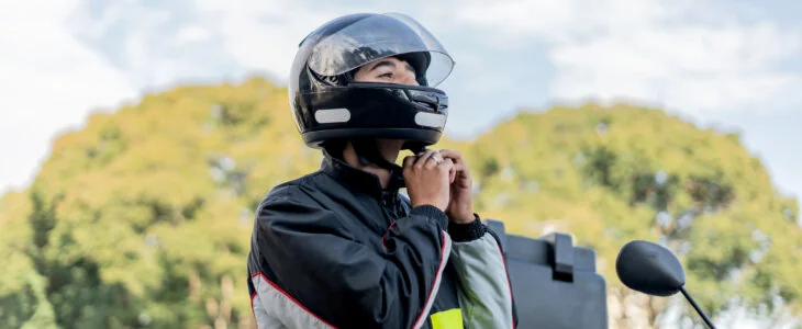 Delivery man removing motorcycle helmet, motoboy.
