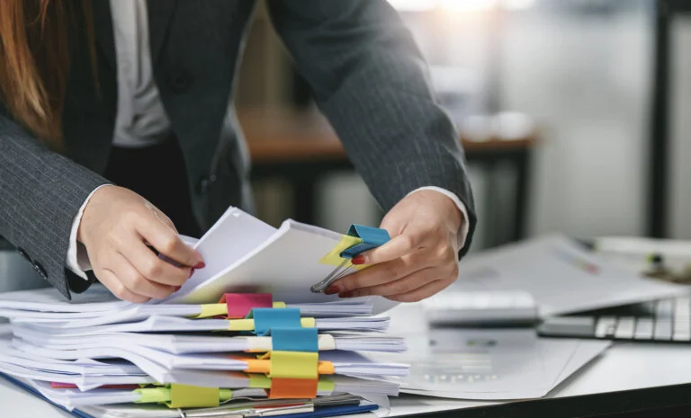Businesswoman hands working in Stacks of paper files